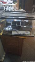 Front view of glass fish tank on wooden table with covers resting on top, cables and filter visible inside.