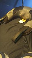 Photo showing black and gray U-shaped neck massager with a control button on the side, lying on a black surface.