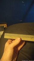Hand held rectangular sharpening stone showing thickness, smooth flat side visible.