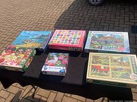 All six puzzles arranged on a table outdoors, showing box artwork and overall lot content