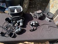 Overview of all items: Olympus E-500 DSLR with lenses, Canon PowerShot SE IS, Pentax Optio S40, camera bag, and accessories.