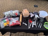 Full view of all baking utensils and tools displayed on a black cloth on the ground.