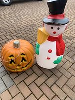 Snowman and pumpkin shown together outside on paving stones, cords visible for lighting