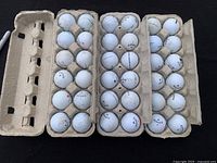 Three open cardboard egg cartons holding 36 golf balls mostly Callaway brand showing used condition with dirt and scuffs.
