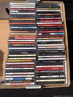 Overview photo showing two rows of stacked music CDs in jewel cases featuring various artists and album spines visible