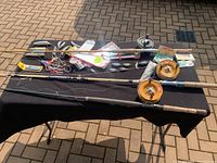 Three fishing rods and reels accompanied by various weights, lures, plugs, and fishing hook setups arranged on a black table outdoors.