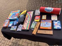 Image showing multiple board and card games laid out on pavement, includes Connect 4, Old Maid, IQ Brain Train Game, and more.
