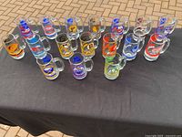 Group photo of 20 NHL hockey team glass beer mugs arranged on black cloth.