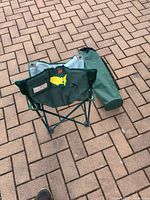Photo of folded green Master's chair with carrying bag on pavement