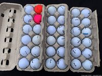 Top-down view of all three trays holding thirty-six golf balls including some colored balls
