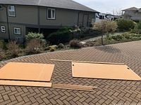 Two peg boards laid on pavement with wooden backing strips and some screws scattered around.