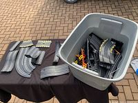 Race track sections arranged on table with bin full of additional parts in background