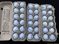 Three dozen Vice golf balls arranged in three egg cartons with various models and markings.