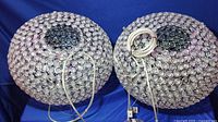 Top view of two crystal orb hanging lamps laid side by side, showing the circular crystal elements and metal frames with electrical cords.