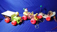Three vintage Fisher Price pull toys displayed in a row on blue background showing full size and shape.