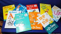 Lot of 9 Dr. Seuss beginner books arranged on blue fabric background. Titles and colorful illustrated covers visible.