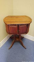 Full view of the antique wooden side table showing top, cabinet doors, and four-legged base.