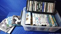Photo of plastic container holding 11 VCR movies with decorative slipcases alongside note cards and cassette holder with tapes.