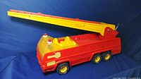 Side view of the large vintage Tonka fire truck showing extended yellow ladder and red metal body.