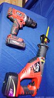 Photo of Skil 18V cordless reciprocating saw and Hyper Tough 20V cordless drill on blue fabric surface