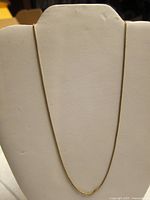 Full view of fine yellow gold chain draped on white jewelry bust