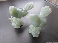Photo of the pair of green jade bird figurines showing their side profiles and detailed carving.