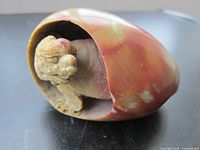 Close-up image of the agate dragon egg carving showing the polished stone with natural coloration and the detailed dragon carving inside the hollowed egg shape.