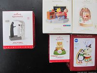 Photo of five Hallmark Keepsake original boxes and one Pillsbury Doughboy ornament box against black background, showing the themed characters on each box.