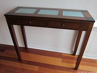 Front view of a wooden console table showing three frosted glass panels on the tabletop and two drawers with knobs below the panels.