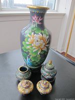 Large tall Asian vase with floral design on a stand and four small colorful decorative pots, one pot is missing its lid.