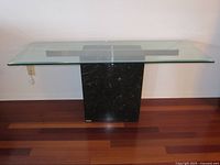 Front view of console table showing clear glass top and black marble base