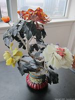 Front view of jade floral sculpture with multi-coloured blossoms in decorative pot on wooden stand