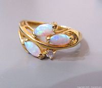 Front and angled view of gold tone ring with three marquise opal stones and a small clear round stone showing color play on stones