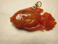 Close-up image showing front view of the red jade fish pendant with detailed carving and metal loop attached