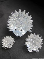 Three Swarovski crystal hedgehog figurines of varying sizes arranged on dark fabric to show details of faceted crystal spikes, black eyes and noses.