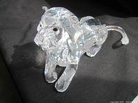 Clear faceted Swarovski crystal lion figurine photographed on black fabric background showing full body and detailing