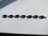 Full length view of the silver tone bracelet with rectangular black stones laid flat showing all linked segments and clasp.