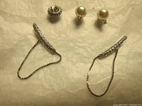 All three earrings displayed together on light soft background showing front view and detail of stones and chains.