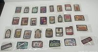 Thirty vintage 1979-1980 Topps Wacky Packages sticker cards laid out on white background, each in protective plastic sleeve, showing colorful parody designs of consumer products.