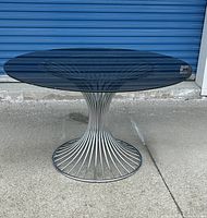 Full front view of the circular smoked glass top and chrome rod pedestal base