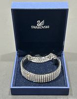 Swarovski crystal bangle placed in blue branded Swarovski box showing bracelet shape and inner cushion.