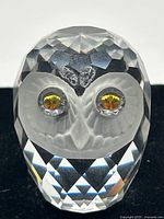 Front close-up image showing the faceted clear crystal owl with frosted face and amber-colored eyes in silver bezel settings.