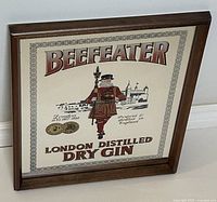 Frontal angled photo of the beige background Beefeater bar mirror sign in wooden frame