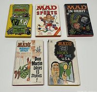 Top view of five vintage Mad paperbacks arranged in a 3-2 grid, shows cover artwork and titles.