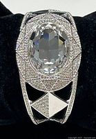Front view of Swarovski crystal open cuff showing large clear oval crystal centerpiece surrounded by pavé crystals in geometric pattern.