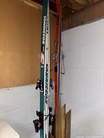 Two pairs of ski poles leaning against a wall, one brown and one blue pair visible