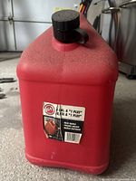 Front view showing label and cap on red plastic Blitz fuel can.