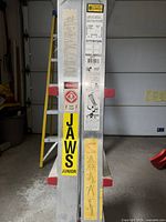 Close-up of ladder showing model number JJT17, safety, instructional and warning labels, and JAWS Junior branding.