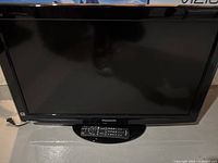 Front view of Panasonic 32-inch LCD TV powered off with remote on stand.