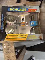 Photo of new Schlage Artisan Series Grade 2 deadbolt and keyed entry set in original packaging showing lifetime finish and security features.